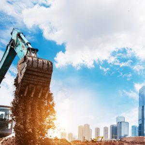 O que é LCI: uma máquina de construção civil e em segundo plano alguns prédios.