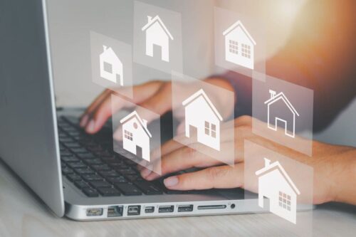 como investir no mercado imobiliário: uma pessoa digitando no notebook e ícones de casinhas aparecendo.