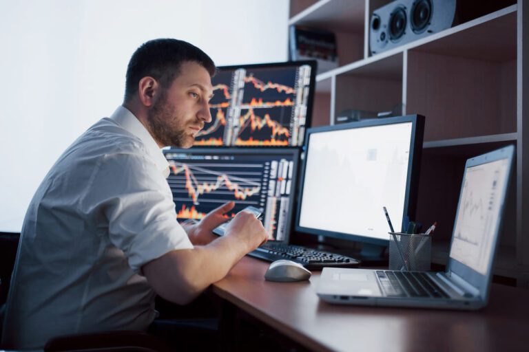 acionista: um homem sentado na frente do computador olhando o gráfico de oscilação do mercado financeiro.