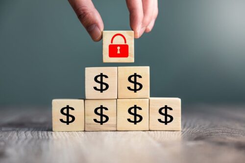 investimento seguro: caixinha de madeiras com o símbolo do $ formando uma piramide e no topo um cadeado vermelho fechado desenhado na última caixinha.