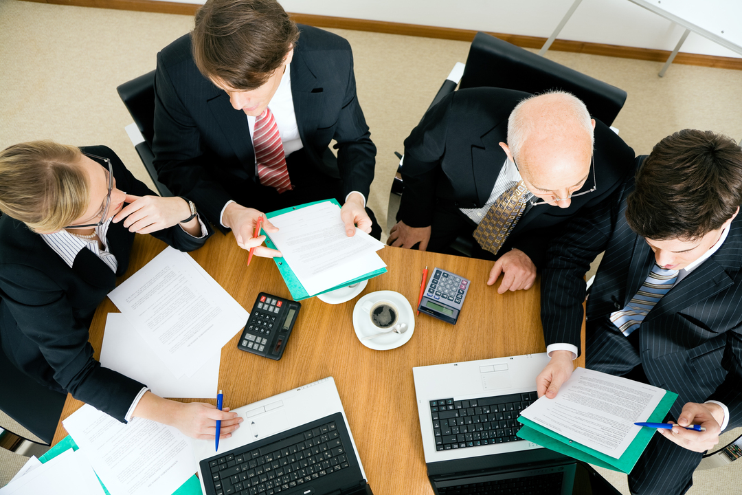 Quatro pessoas de terno analisam informações em uma reunião do Copom, o Comitê de Política Monetária