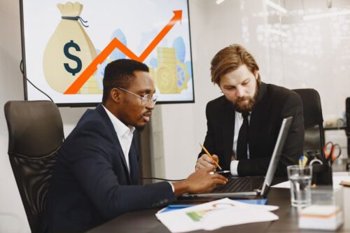 decisão de investimento: dois homens analisando o mercado de ações para escolher os melhores investimentos dentro do perfil de investidor.
