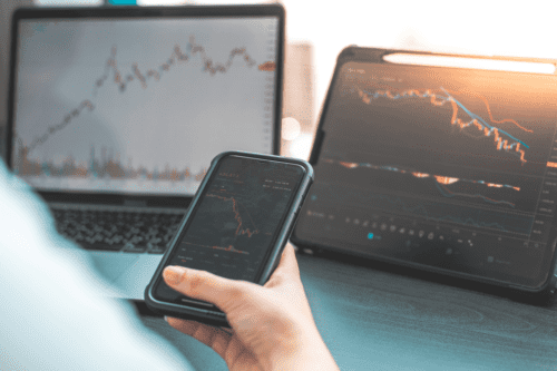 stock picking: uma pessoa acompanhando as oscilações do mercado financeiro pelo notebook, celular e tablet.