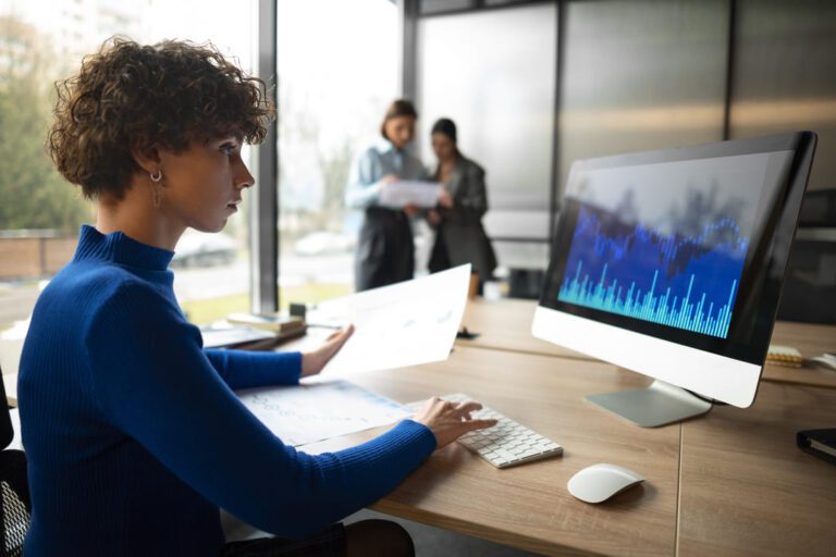 como empreender: uma mulher de cabelo ondulados, analisando, dados sobre o mercado financeiro no computador.
