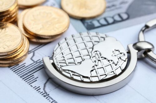 sanções econômicas: algumas moedas douradas e uma representação de um globo terrestre em medalha.