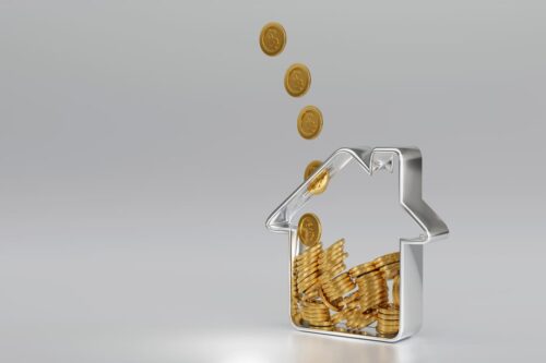 prazo resgate fundo imobiliário: um cofrinho de dinheiro em formado de uma casa, com moedas douradas dentro e algumas saindo.