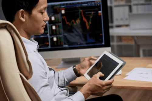 tipos de debentures: um homem acompanhando as oscilações do mercado financeiro por meio do tablet.