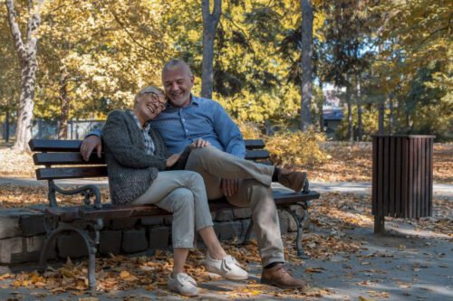 aposentadoria: um casal de idosos felizes sentados no banco de um parque.