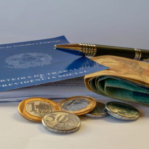 inss: uma carteira de trabalho, uma caneta, duas moedas de um real e três de 50 centavos e algumas notas de dinheiro.