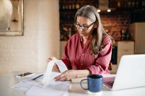 reforma tributária: uma senhora de uns 60 anos olhando as taxas de tributos fiscais.