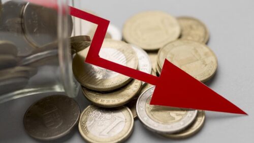 Seta vermelha em declínio representando o indicador EBITDA sobre moedas despejadas em superfície.