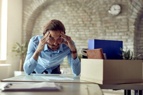 Um jovem trabalhador descontente, sofrendo de dor de cabeça após ser demitido do trabalho no escritório. Após o aumento da inadimplência em janeiro