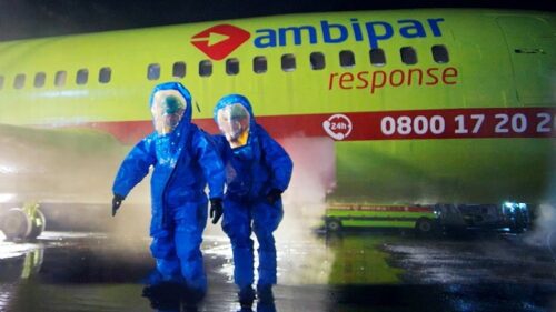 pessoas em trajes de proteção perto de um avião da Ambipar