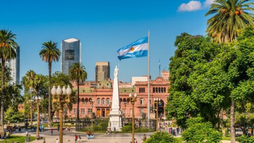 uma bandeira da Argentina em um poste com a cidade de fundo