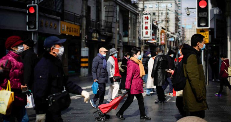 um grupo de pessoas andando em uma rua da China com máscaras