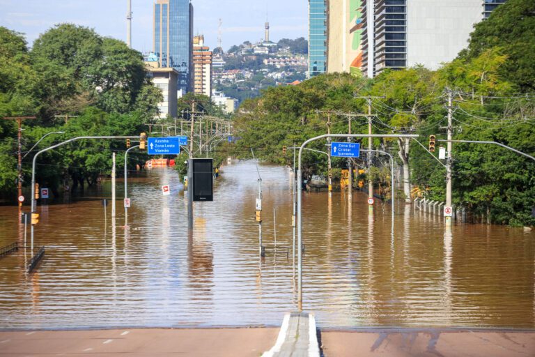 uma rua inundada com árvores e edifícios ao fundo