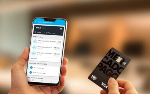 uma mão segurando um telefone com aplicativo do Mercado pago e um cartão de crédito preto do Mercado Pago