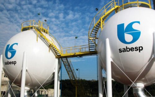 grandes tanques brancos com logotipo da Sabesp azul e escadas amarelas no fundo céu azul e poucas nuvens