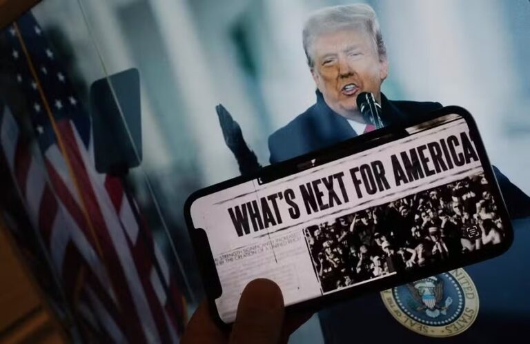uma pessoa segurando um telefone na frente da foto de Trump