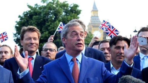 Nigel Farage de terb e gravata na frente de pessoas com bandeiras do Reino Unido