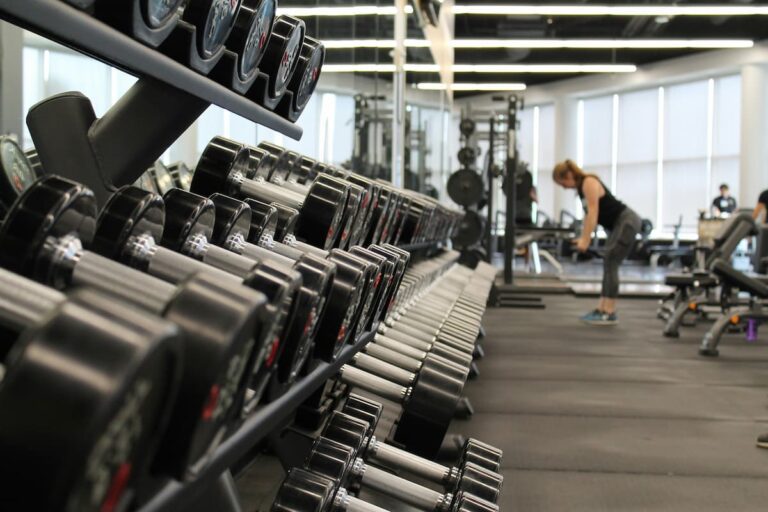 Academia moderna com diversas halteres alinhadas, destacando o ambiente de treino. Franquias esportivas oferecem infraestrutura completa.