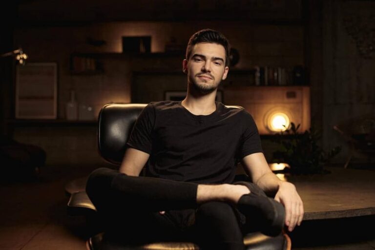 Imagem de Breno Perrucho sentado em uma cadeira, vestindo uma camisa preta, referência no mercado de investimentos.