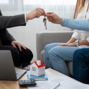 Agente entregando chaves a um casal, representando a aquisição de imóvel por meio de consórcio imobiliário.