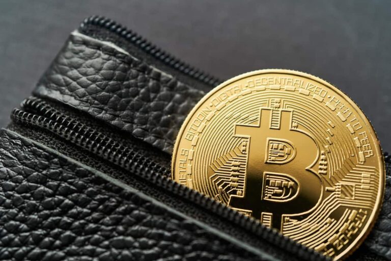 Imagem de uma carteira Bitcoin com uma moeda física de Bitcoin visível, simbolizando o armazenamento de criptomoedas.