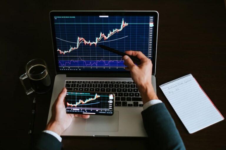 Gráfico de análise de ações em laptop e celular, representando estratégias para escolher os melhores BDRs para investir.