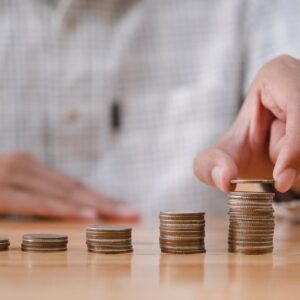 Pessoa empilhando moedas, simbolizando investimento e quanto rende 1 milhão no Tesouro Direto.