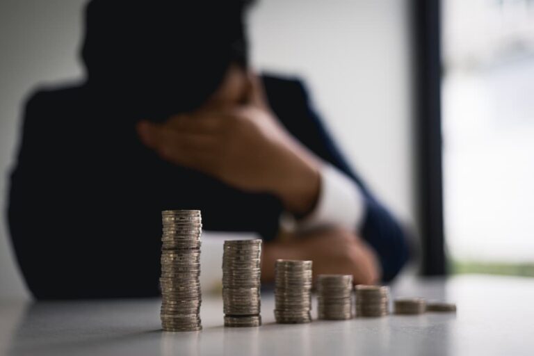 Pilhas de moedas decrescentes e um homem preocupado ao fundo, representando que dividendos fecham 2024 com queda de 9%.