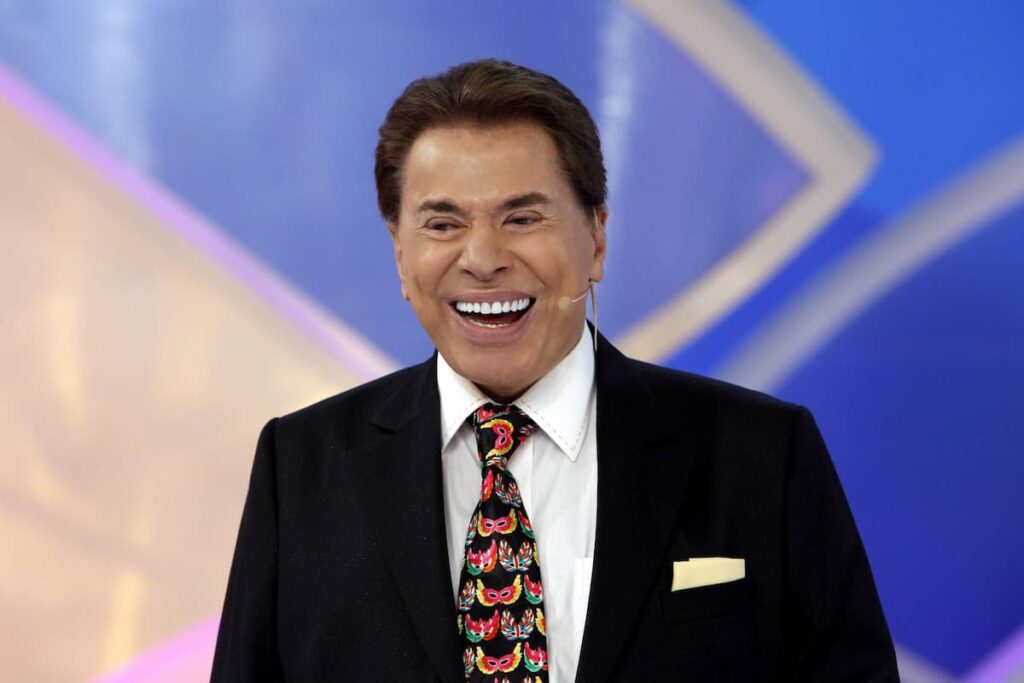 Silvio Santos sorrindo enquanto apresenta o Programa Silvio Santos.
