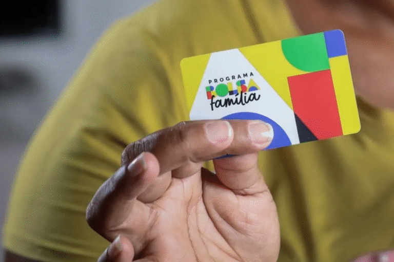 Pessoa segurando cartão do programa Bolsa Família com informações sobre calendário de pagamentos de junho de 2025.