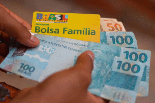 Foto do cartão do programa Bolsa Família em meio à cédulas de dinheiro.
