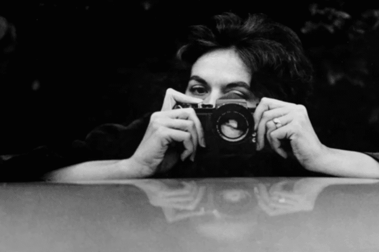 Foto em preto e branco de fotógrafa Claudia Andujar, segurando uma maquina fotográfica.