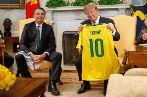 Foto de Donald Trump segurando uma camisa do Brasil, ao lado de Jair Bolsonaro.