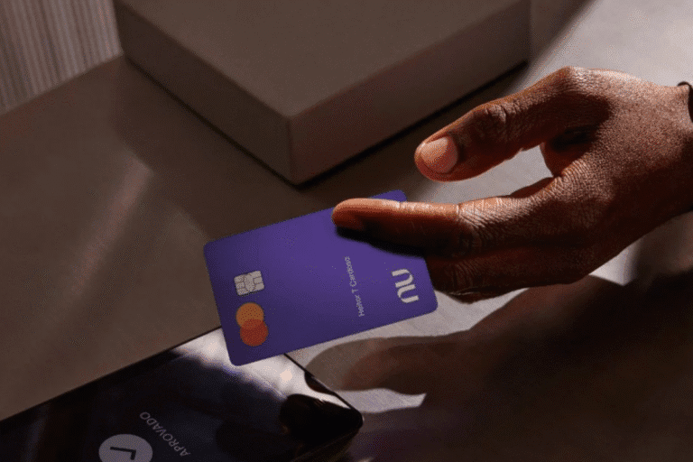 Foto de uma pessoa segurando um cartão da Nubank em frente a um telefone.