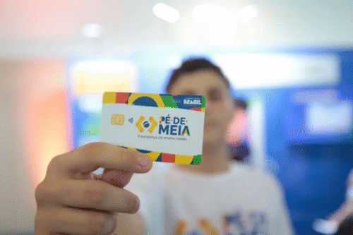 Foto de uma pessoa segurando o cartão do programa Pé-de-Meia.