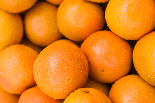 Pilha de laranjas cobertas por gotas de água.