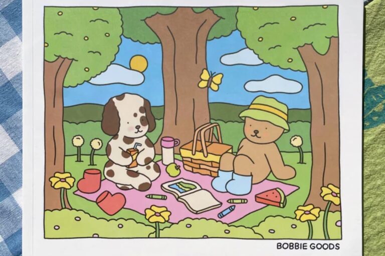 Ilustração do livro Bobbie Goods com um piquenique fofo entre um ursinho e um cachorro em um cenário colorido e alegre.