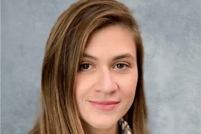 Retrato de uma mulher sorridente com cabelo castanho claro, usando blusa com estampa e fundo cinza, representando uma imagem de alta qualidade para uso profissional.