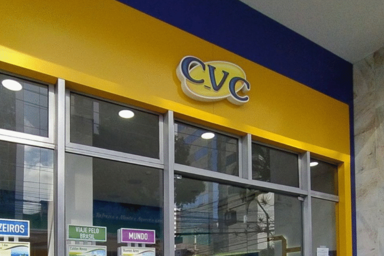 Fachada de uma loja CVC com logo amarelo e azul, destaque para a entrada de vidro e cartazes informativos na frente, localizada no Brasil.