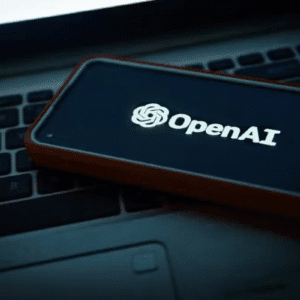 Imagem de um smartphone exibindo o logo da OpenAI, colocado sobre um teclado de laptop, representando tecnologia e inteligência artificial.