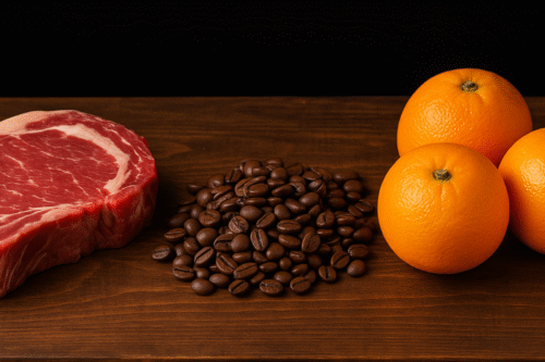 Imagem de uma peça de carne vermelha ao lado de grãos de café e algumas laranjas, destacando ingredientes naturais para alimentação saudável.