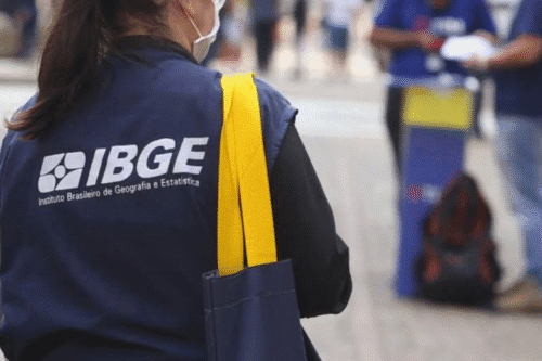 Pessoa com vestimenta do Instituto Brasileiro de Geografia e Estatística (IBGE) participando de atividade ao ar livre.