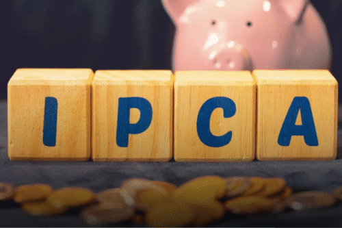 Blocos de madeira representando a sigla IPCA com uma porca de porquinho ao fundo, simbolizando economia e inflação no Brasil.
