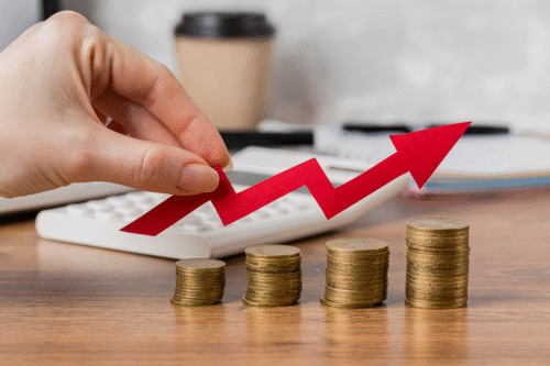 Imagem de uma mão ajustando uma seta vermelha crescente, sobrepostas a pilhas de moedas, simbolizando crescimento financeiro e investimento inteligente em negócios.