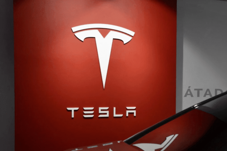 Imagem da Logo da Tesla em destaque na parede de uma loja, com fundo vermelho e o logo branco, representando inovação e tecnologia no setor de veículos elétricos.