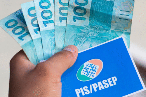Mão segurando notas de 100 reais e um cartão do programa PIS/PASEP, representando benefício social do Brasil.