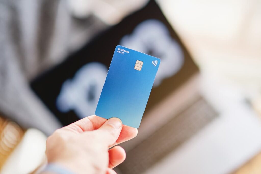 Indivíduo com um cartão de crédito na mão, posicionado diante de um laptop, sugerindo uma compra digital com Pix.